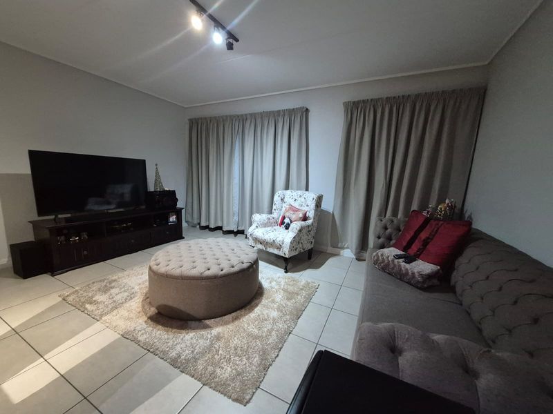 A comfortable living room featuring neutral tiled flooring and modern track lighting, providing a functional and well-lit space for relaxation.