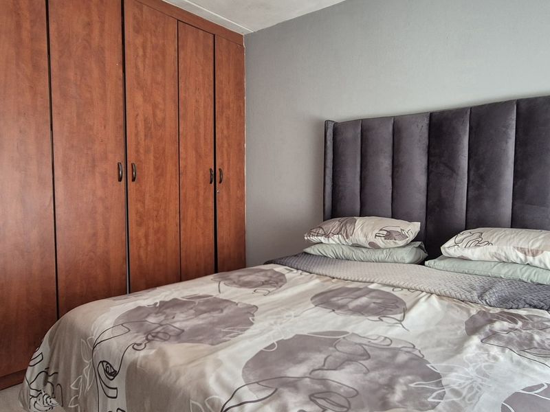 A bedroom featuring floor-to-ceiling wooden built-in cupboards, providing ample storage space within the room.