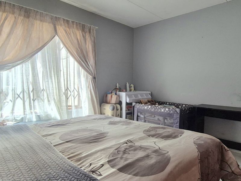 A standard bedroom featuring tiled flooring and a window fitted with a security gate.