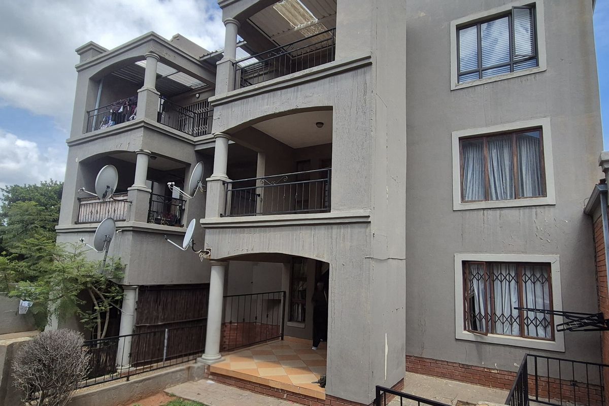 Rear elevation of a multi-story apartment building featuring stacked balconies, security window bars, and concrete structural columns.