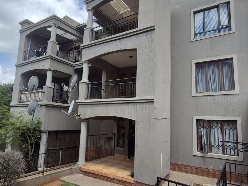 Rear elevation of a multi-story apartment building featuring stacked balconies, security window bars, and concrete structural columns.