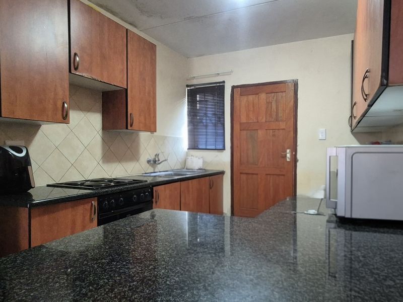 A functional kitchen featuring granite countertops, wooden cabinetry, and a built-in oven, requiring cosmetic updates to improve its overall aesthetic and condition.