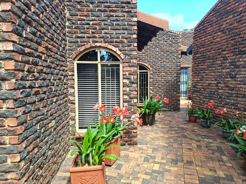 A charming, private courtyard featuring rustic face brick walls, arched windows, and durable paved flooring, creating a welcoming outdoor transition space.