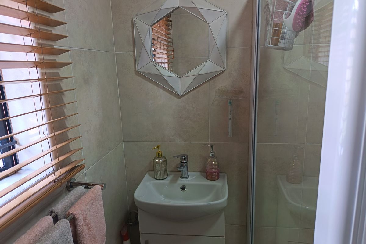 Compact bathroom featuring a modern vanity basin, tiled walls, and a glass-enclosed shower unit.
