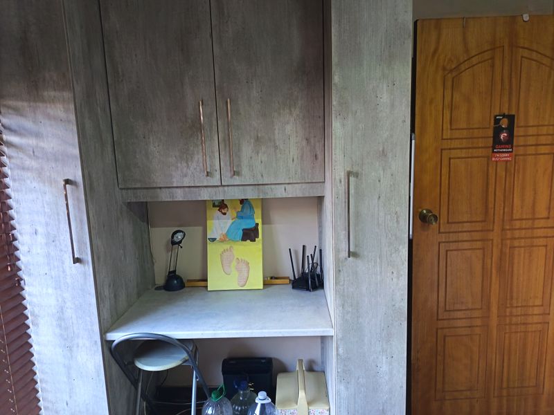 A bedroom featuring built-in cabinetry with a integrated desk workspace and a solid wood door.