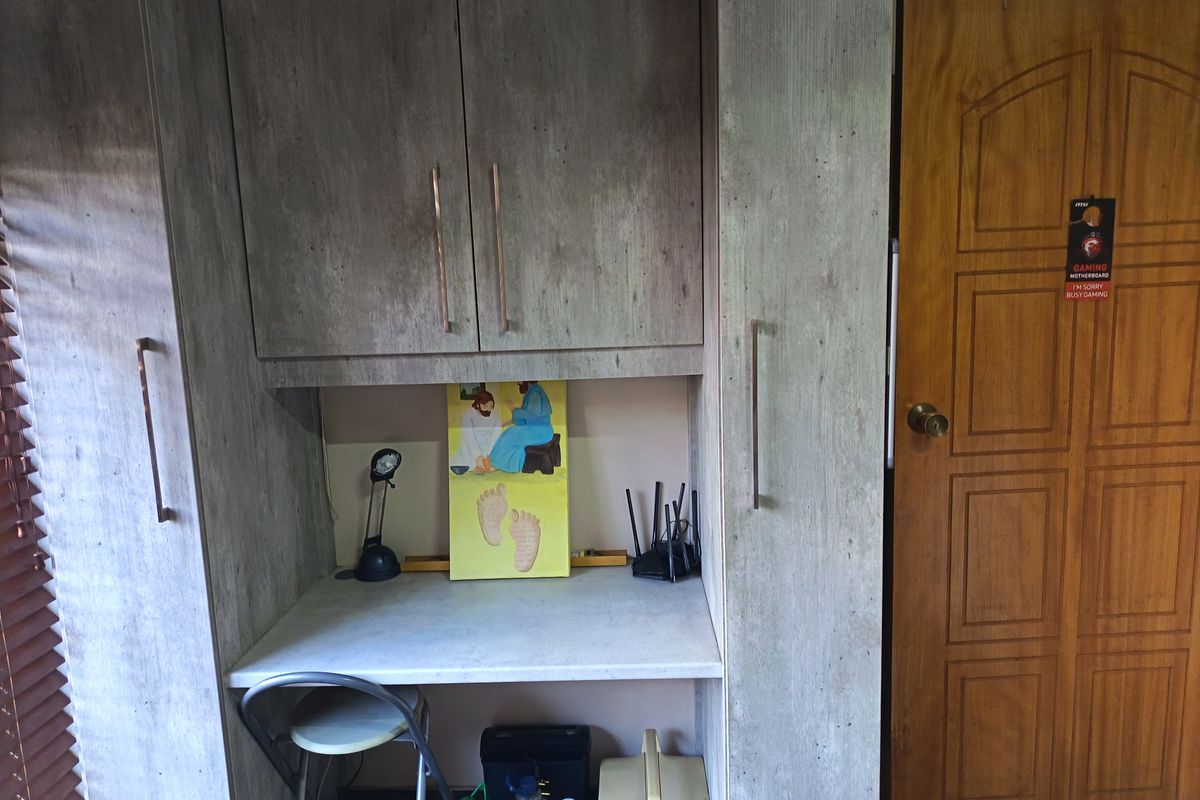 A bedroom featuring built-in cabinetry with a integrated desk workspace and a solid wood door.