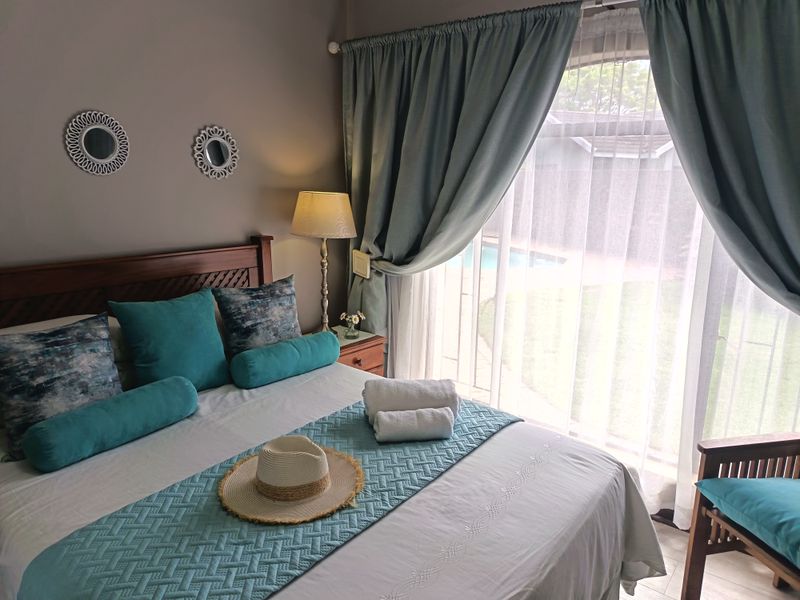 A well-maintained bedroom featuring tiled flooring and a large sliding glass door that provides direct access to the outdoor pool area.