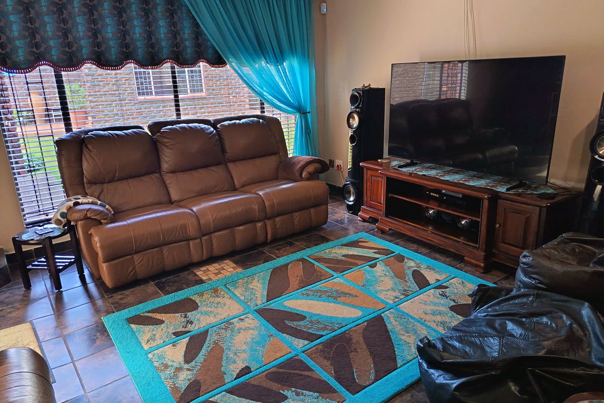 A comfortable living room featuring tiled flooring and a large window, providing a functional space for relaxation and entertainment.