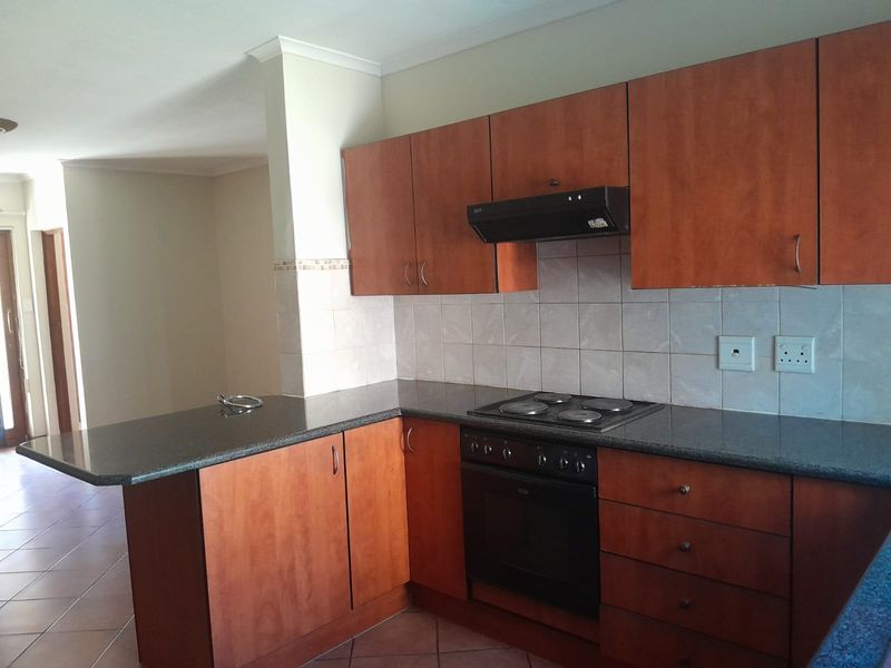 A functional kitchen featuring wooden cabinetry, granite countertops, a built-in oven, electric hob, and a breakfast nook, offering a practical layout for daily use.