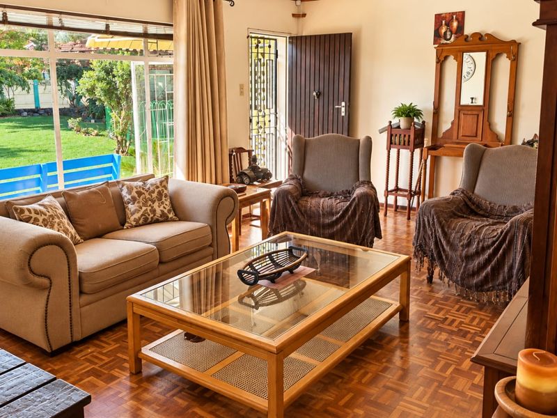 A bright and inviting living room featuring classic parquet flooring and large sliding glass doors that provide seamless access to the garden.