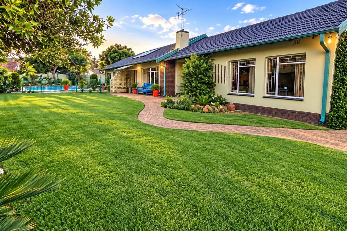 Well-maintained rear garden featuring a manicured lawn, paved pathway, and a swimming pool, complemented by a neat brick and tiled roof exterior.