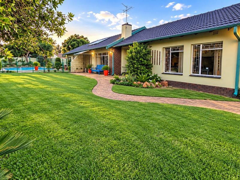 Well-maintained rear garden featuring a manicured lawn, paved pathway, and a swimming pool, complemented by a neat brick and tiled roof exterior.
