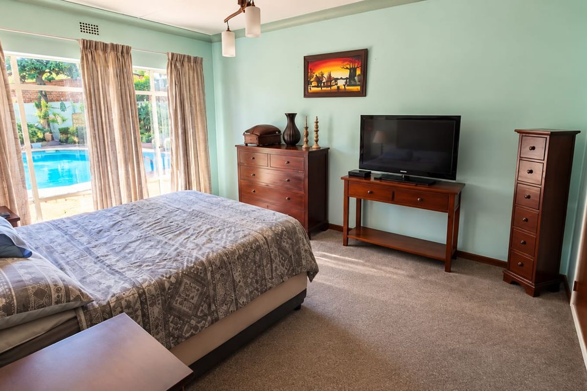 A bedroom featuring carpet flooring, built-in wardrobe, and sliding glass doors providing direct access to the outdoor pool area.
