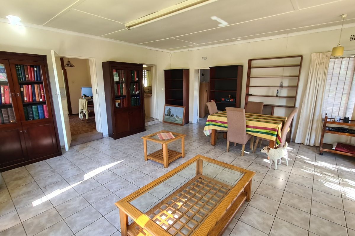 Spacious living area featuring tiled flooring and built-in shelving units, offering a versatile layout with direct access to adjacent rooms.