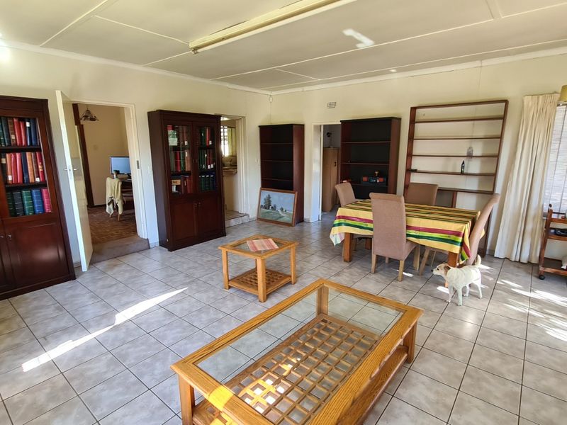 Spacious living area featuring tiled flooring and built-in shelving units, offering a versatile layout with direct access to adjacent rooms.