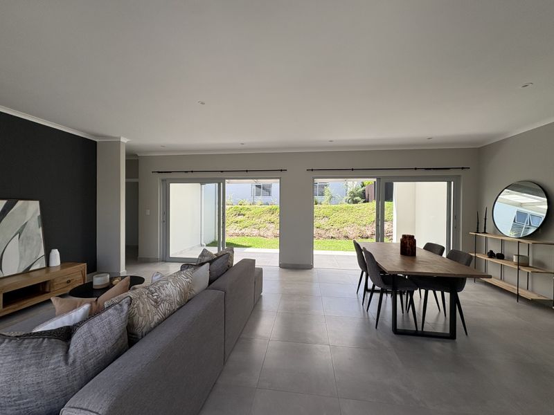 Spacious open-plan living and dining area featuring large sliding glass doors that provide seamless access to the outdoor patio and garden.