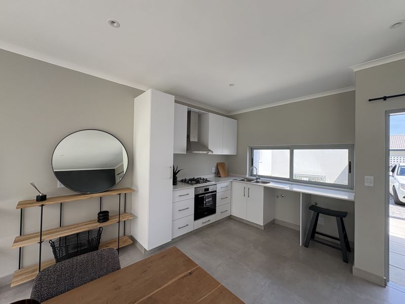 Modern kitchen featuring white cabinetry, gas hob, built-in oven, extractor fan, and a stainless steel sink with tiled flooring and recessed lighting.