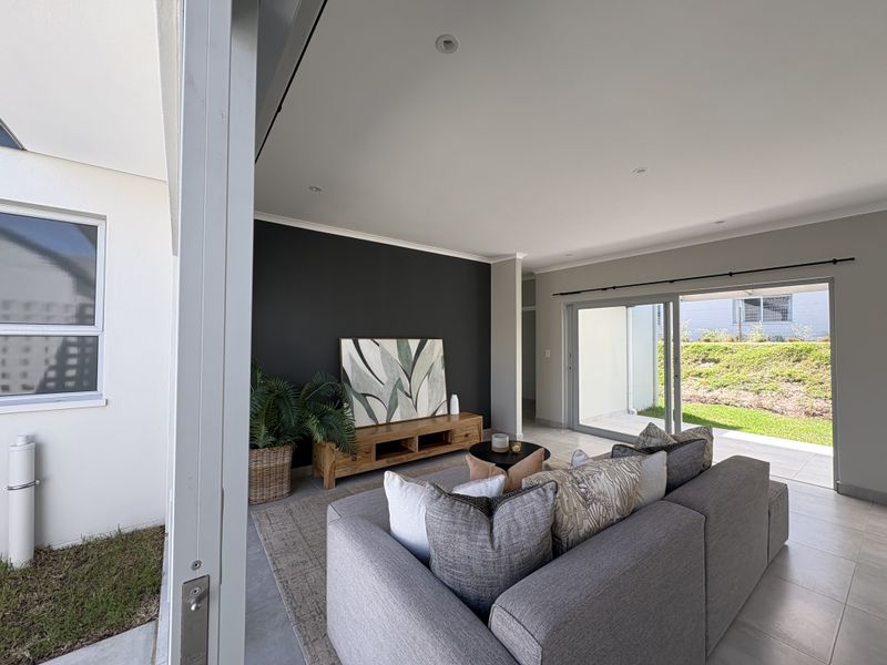 Modern open-plan living area featuring large sliding glass doors that provide seamless access to the outdoor patio and garden.