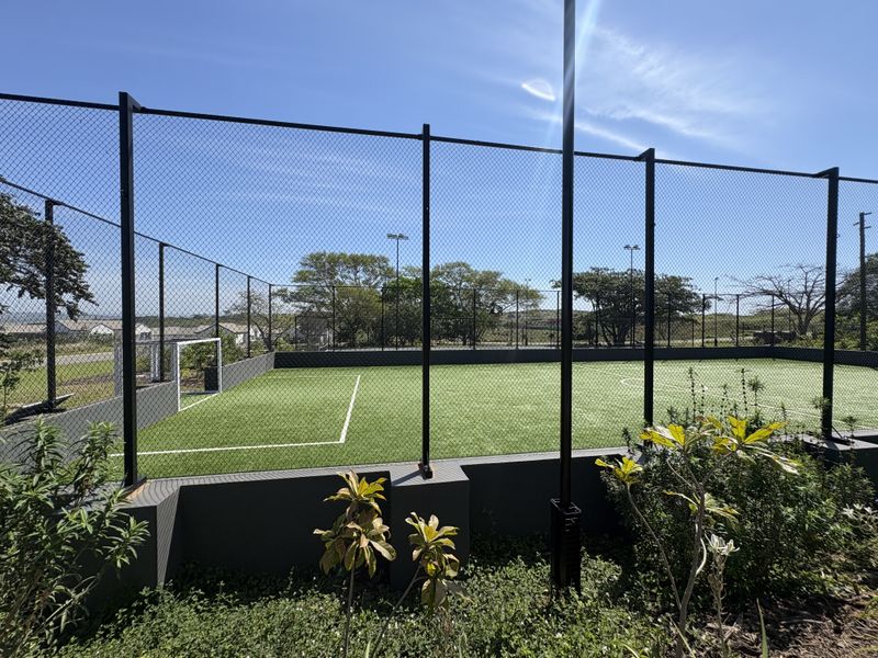 A well-maintained outdoor sports facility featuring artificial turf, perimeter fencing, and floodlighting, suitable for recreational soccer or multi-purpose use.
