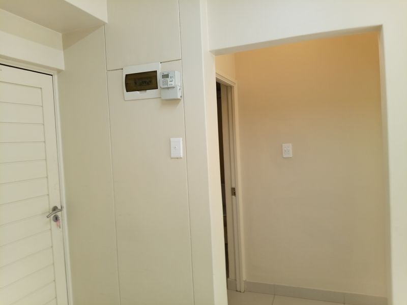 A clean and neutral hallway area featuring an integrated electrical distribution board and access to adjacent rooms.