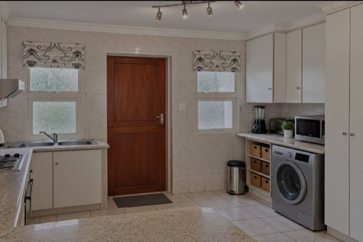 A functional kitchen featuring granite countertops, ample built-in cabinetry, tiled backsplash, and integrated appliances, offering a clean and practical workspace.