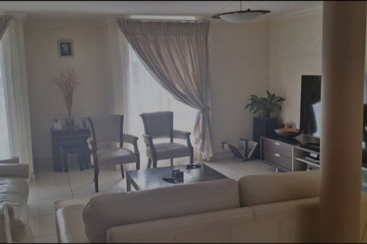 A spacious living room featuring tiled flooring and a structural column, offering a comfortable and functional layout for relaxation.