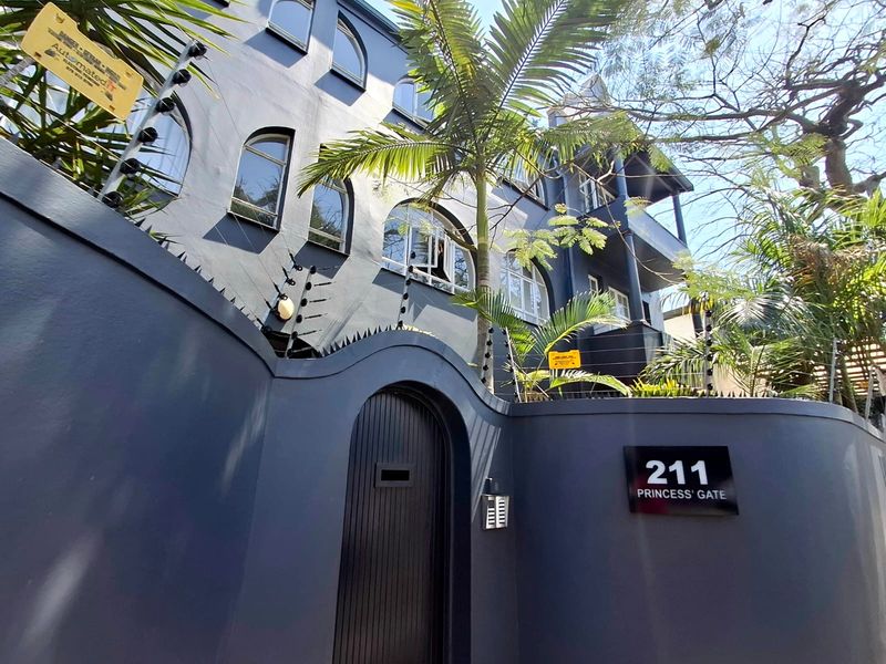 Front elevation of Princess Gate apartment complex featuring a secure boundary wall, electric fencing, and arched architectural window detailing.