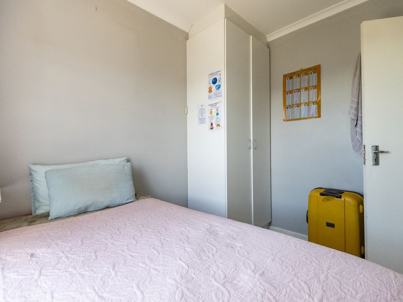 A functional bedroom featuring a built-in wardrobe and neutral wall finishes, providing a practical space for rest.