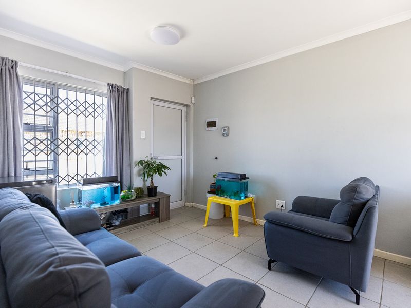 A living room featuring tiled flooring, a window with security bars, and a door leading to the exterior.