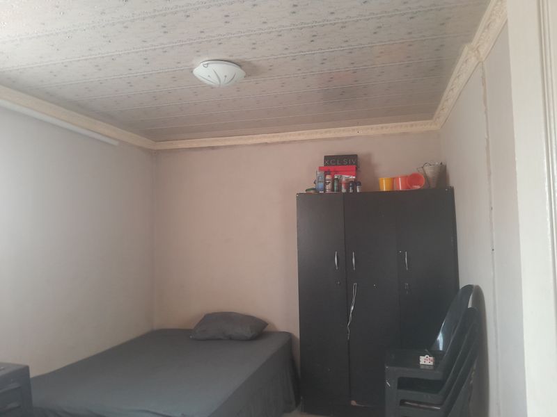 A bedroom featuring a textured ceiling with decorative molding. The space requires cosmetic updates to improve the overall finish and appeal.