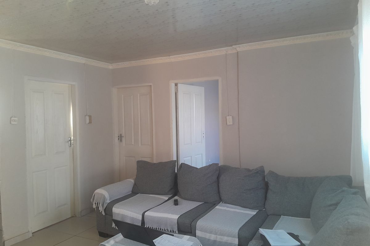 A living room featuring tiled flooring, ceiling cornicing, and multiple internal doors leading to adjacent rooms.