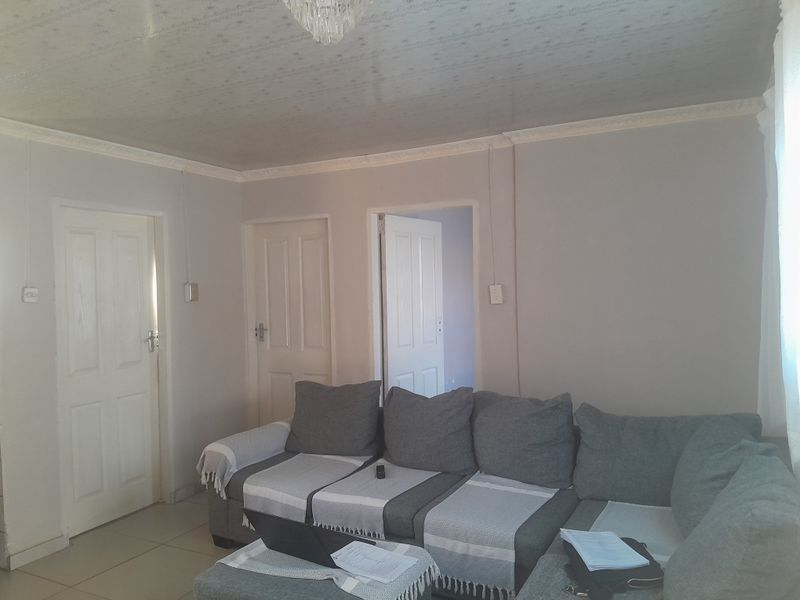 A living room featuring tiled flooring, ceiling cornicing, and multiple internal doors leading to adjacent rooms.