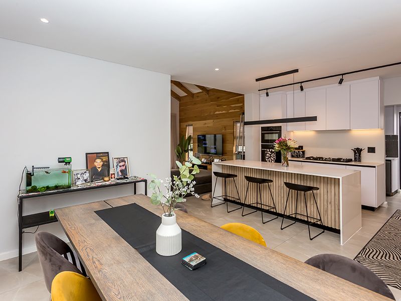Modern open-plan living area featuring a sleek kitchen with a central island, built-in appliances, and stylish timber wall accents.