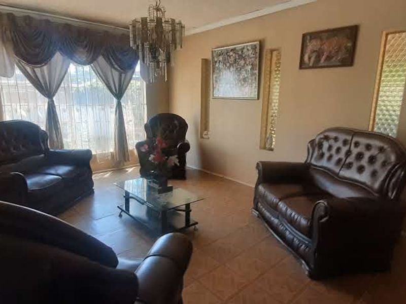 A living room featuring tiled flooring, decorative wall niches, and glass block accents, offering a traditional layout with natural light.