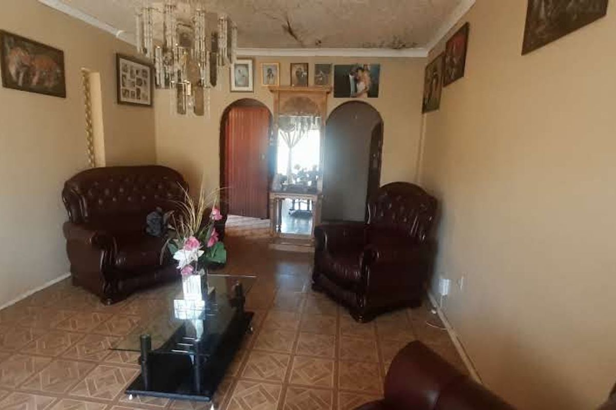 A living room featuring tiled flooring and arched doorways, currently showing visible signs of ceiling water damage and wear.