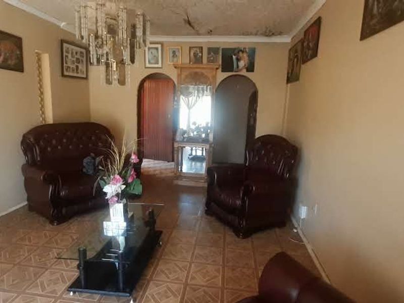 A living room featuring tiled flooring and arched doorways, currently showing visible signs of ceiling water damage and wear.