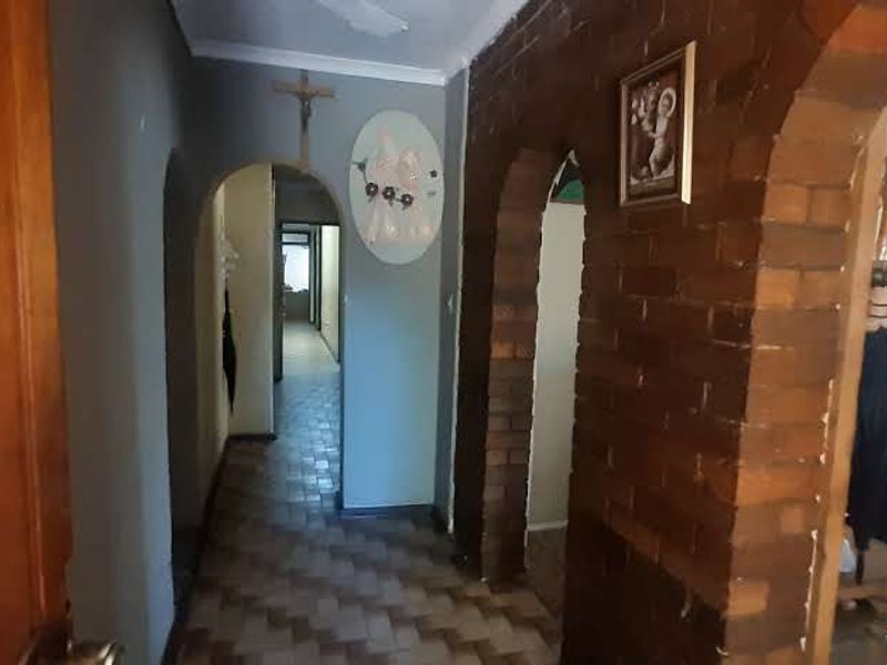 A hallway featuring distinctive brick archways and tiled flooring, connecting various living spaces within the home.
