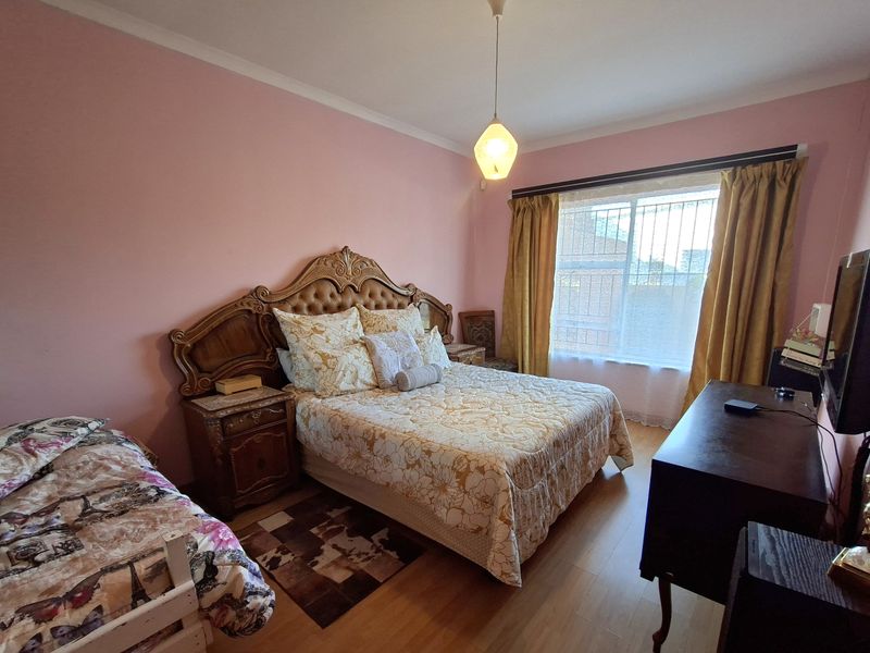 A bedroom featuring laminate flooring, a coved ceiling, and a window fitted with security bars.