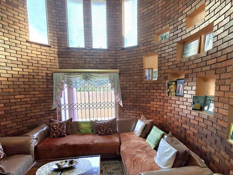 A unique circular living room featuring striking exposed brick walls, built-in display niches, and high ceilings with abundant natural light from vertical windows.