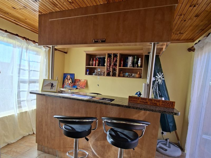 A dedicated home bar area featuring a built-in counter, timber-clad ceiling with recessed lighting, and tiled flooring, creating a functional entertainment space.