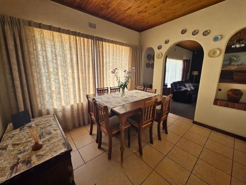 Dining room featuring ceramic floor tiles, a timber ceiling, and an arched doorway leading to an adjacent living area.