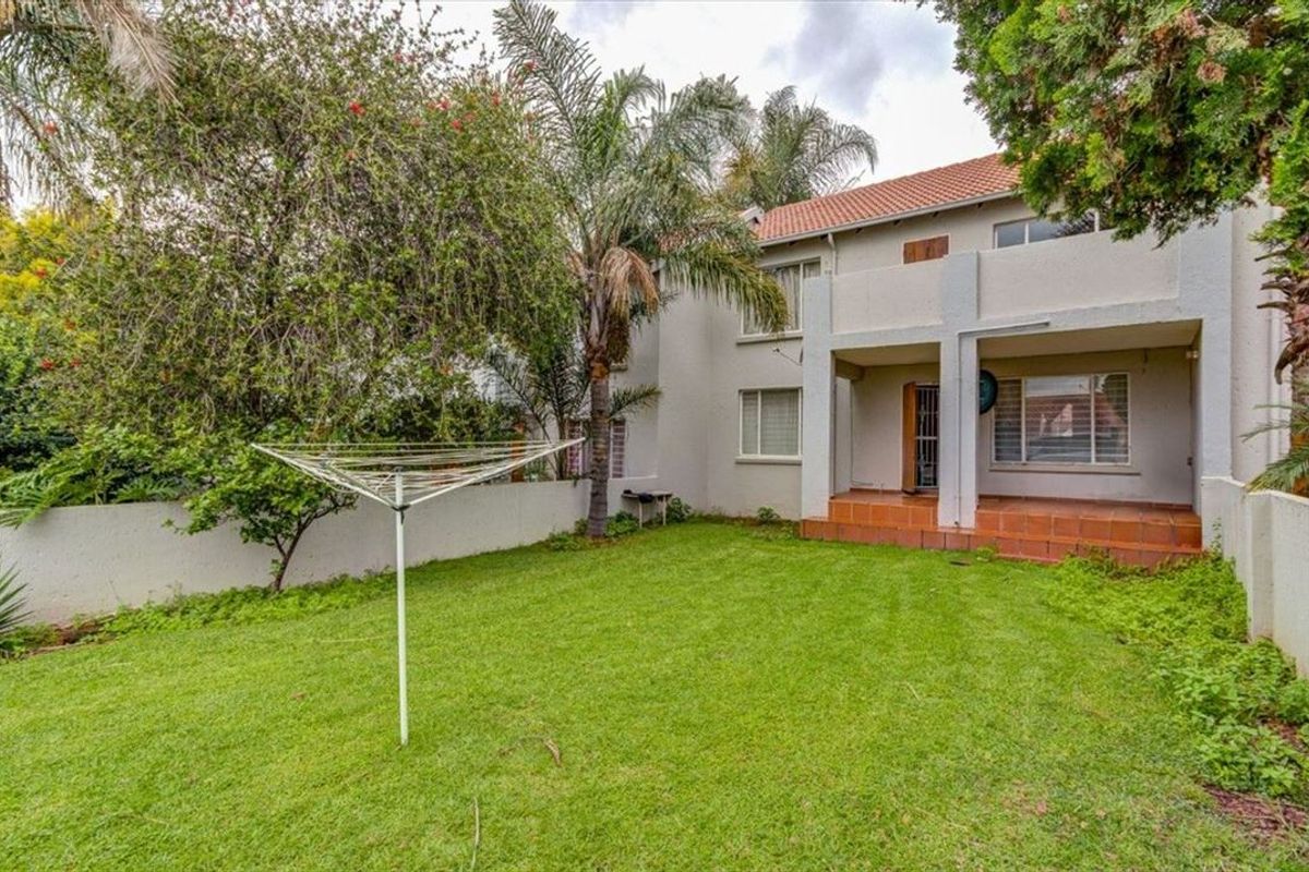 Rear view of the townhouse featuring a private garden, lawn, and a covered tiled patio area.