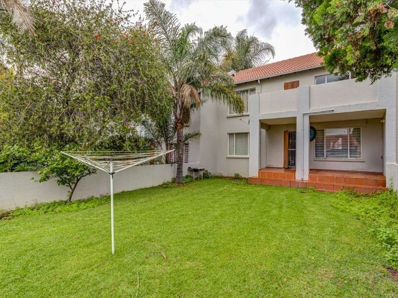 Rear view of the townhouse featuring a private garden, lawn, and a covered tiled patio area.
