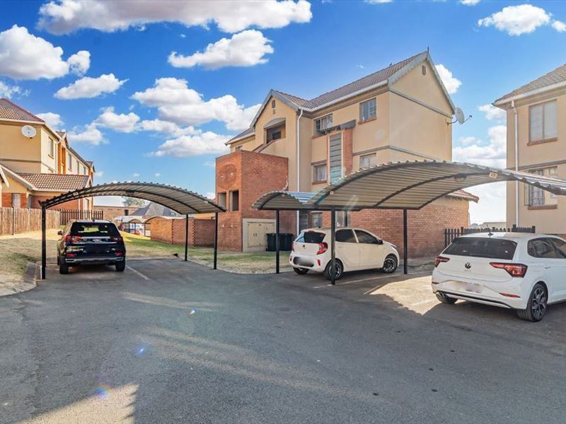 Exterior view of the apartment complex featuring dedicated covered parking bays and paved driveway access.