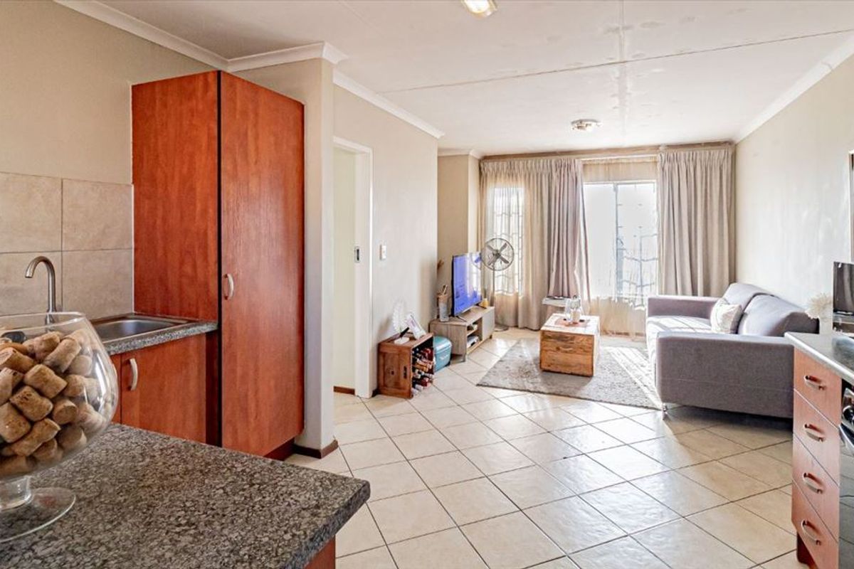Open-plan living area featuring tiled floors, a functional kitchen with granite countertops, and direct access to a balcony through sliding doors.