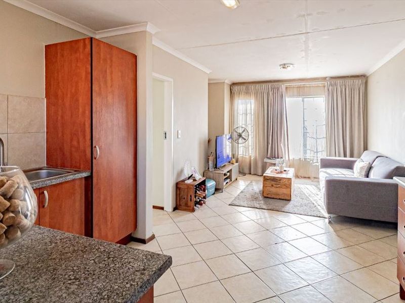 Open-plan living area featuring tiled floors, a functional kitchen with granite countertops, and direct access to a balcony through sliding doors.
