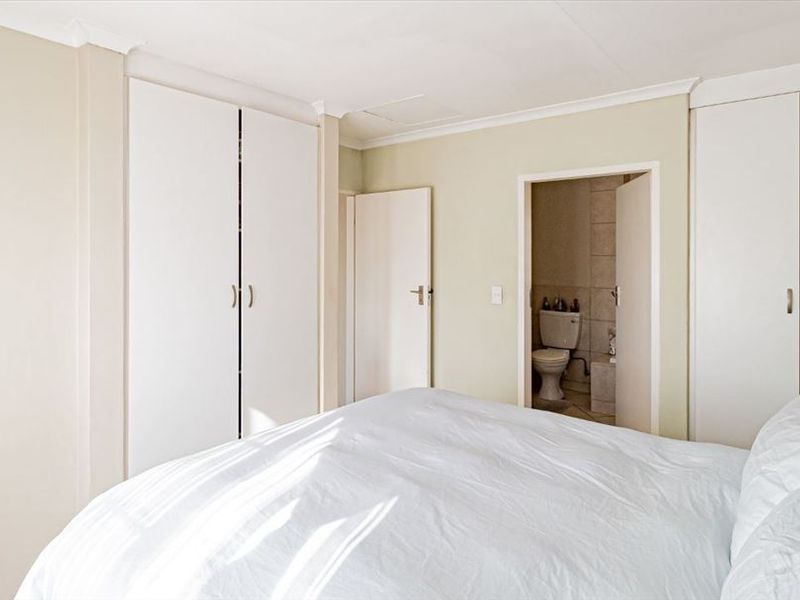 A bedroom featuring built-in cupboards and direct access to an en-suite bathroom.