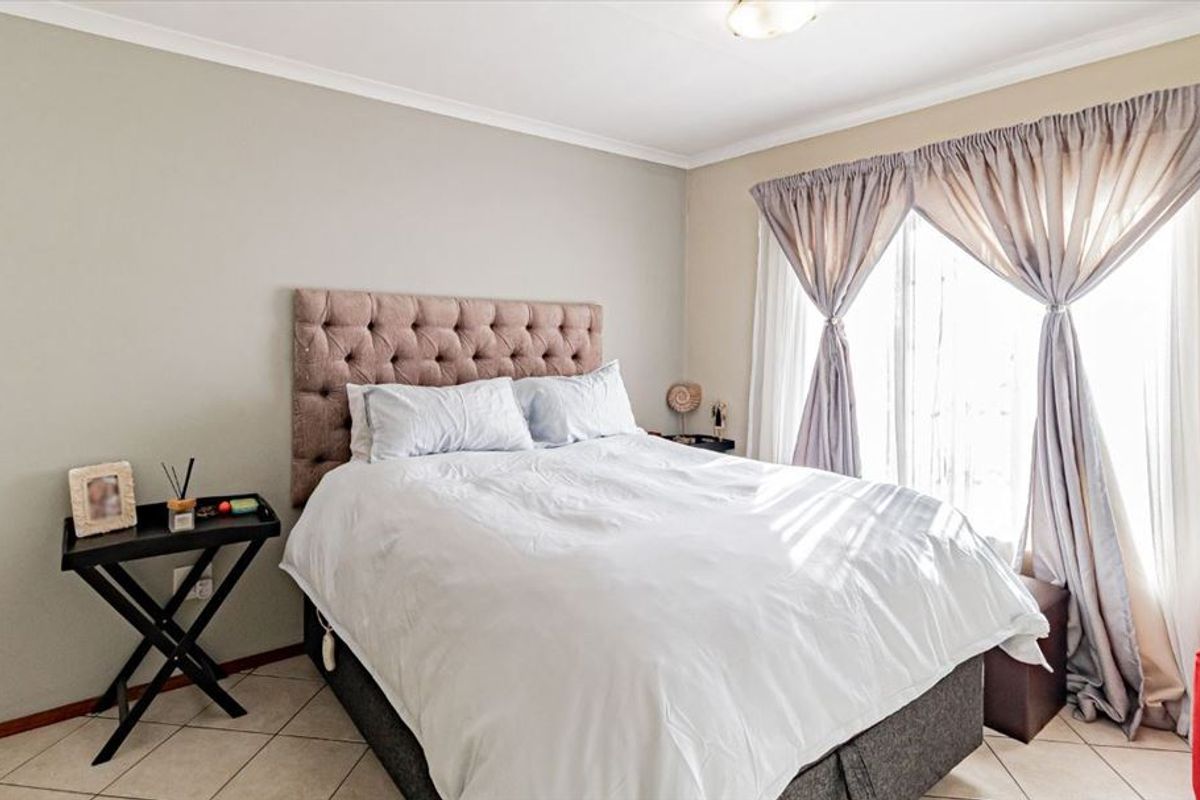 A well-lit bedroom featuring tiled flooring and neutral wall tones, offering a comfortable and functional living space.