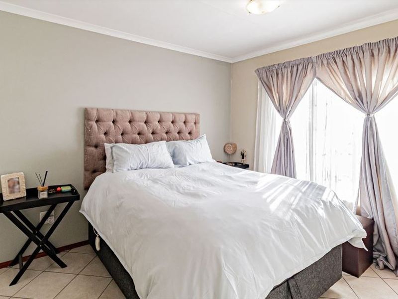 A well-lit bedroom featuring tiled flooring and neutral wall tones, offering a comfortable and functional living space.