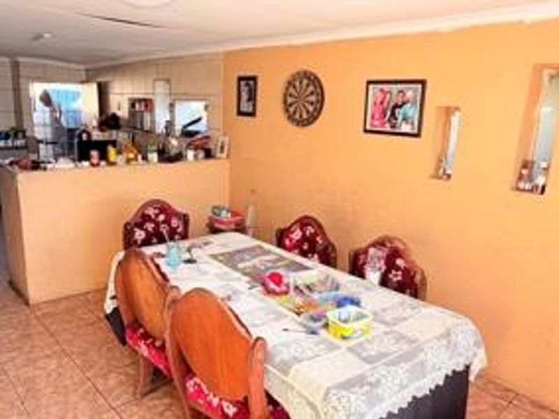 Open plan dining and kitchen area featuring tiled flooring, a breakfast bar, and recessed wall niches. The space requires ceiling repairs and cosmetic updates.